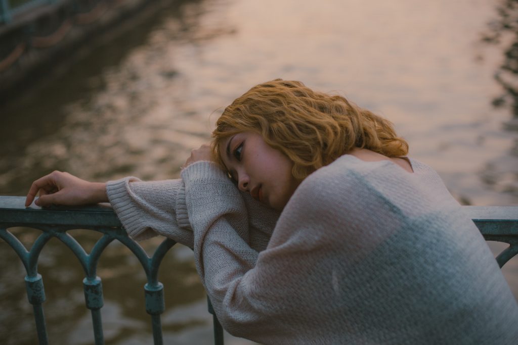 Sad Yong Lady on a bridge above a river